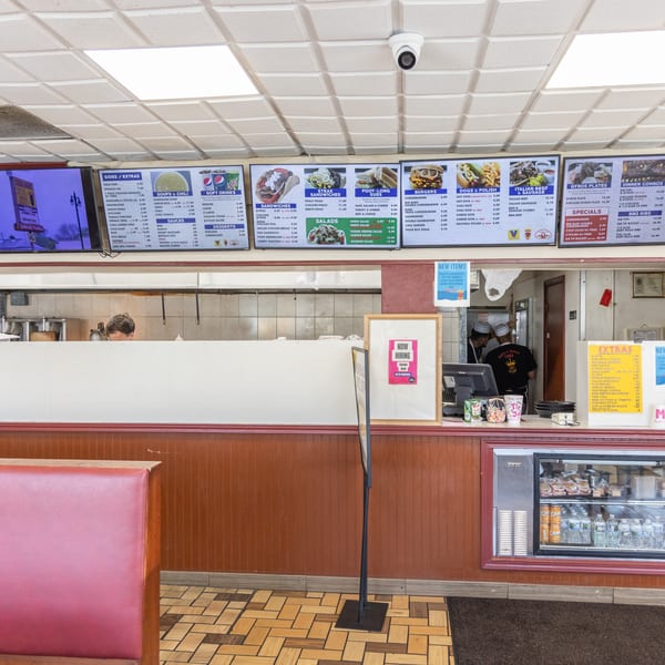 Interior view of a casual restaurant with menu boards, a counter, and a red booth.