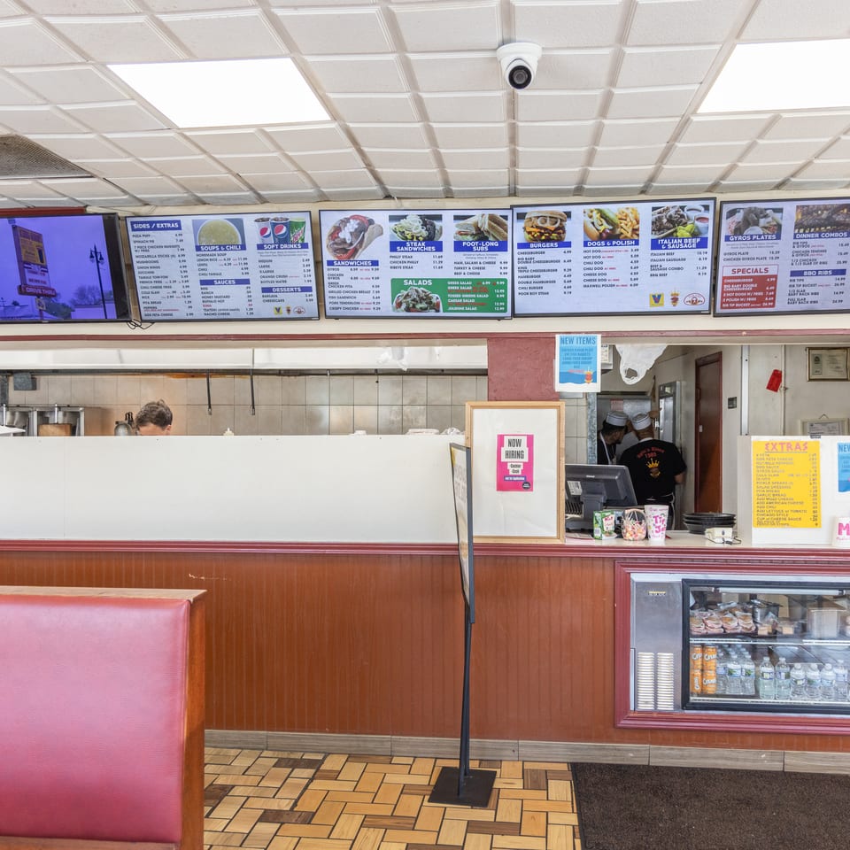 Interior view of a casual restaurant with menu boards, a counter, and a red booth.